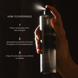 Hand holding a spray bottle with usage instructions on a dark background